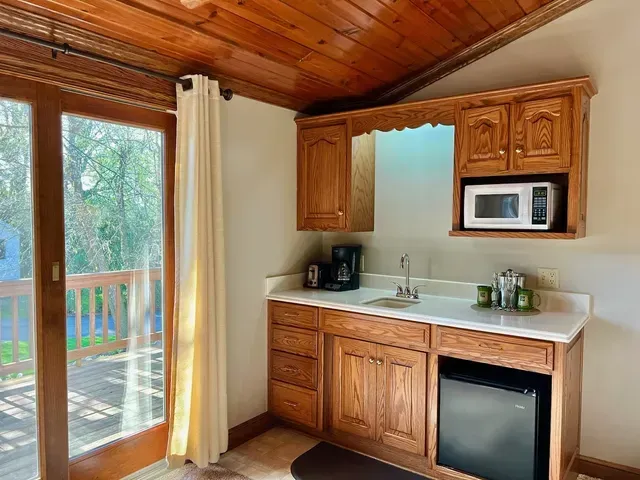 Small kitchenette with microwave, sink, and mini-fridge next to a glass door leading to a deck.