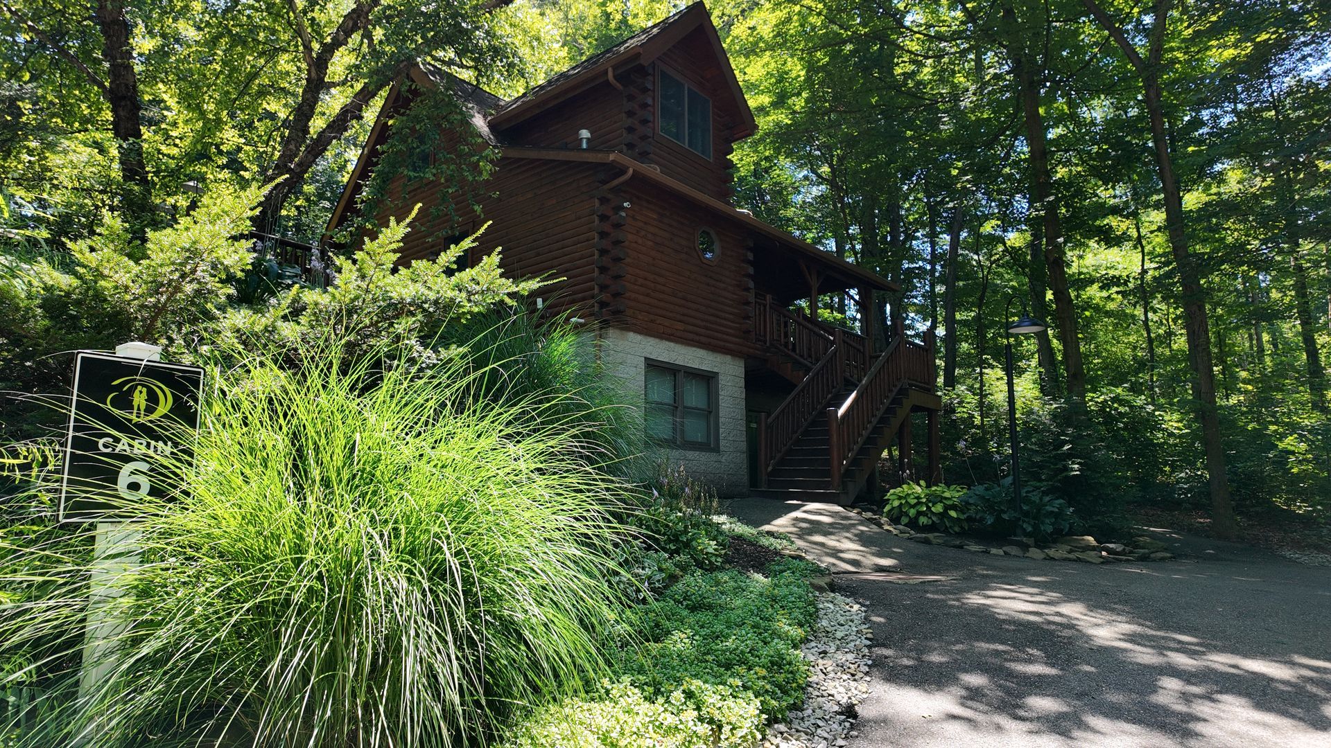 Wooden cabin nestled amongst trees, with a stone foundation and dark brown exterior.