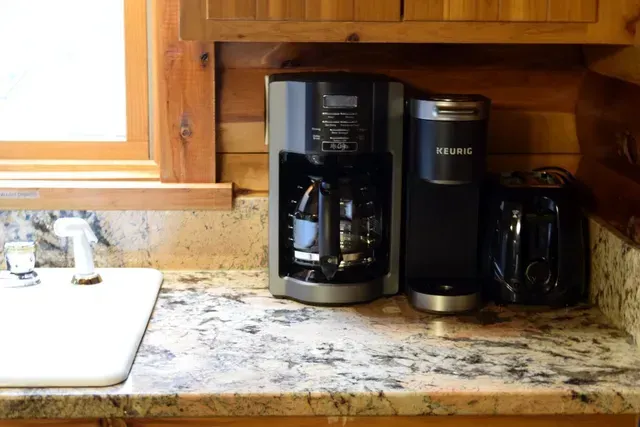 Coffee maker, Keurig, and toaster on a granite countertop in a kitchen.