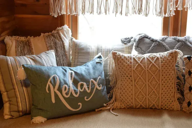 Cozy window seat with various decorative pillows, including one that says