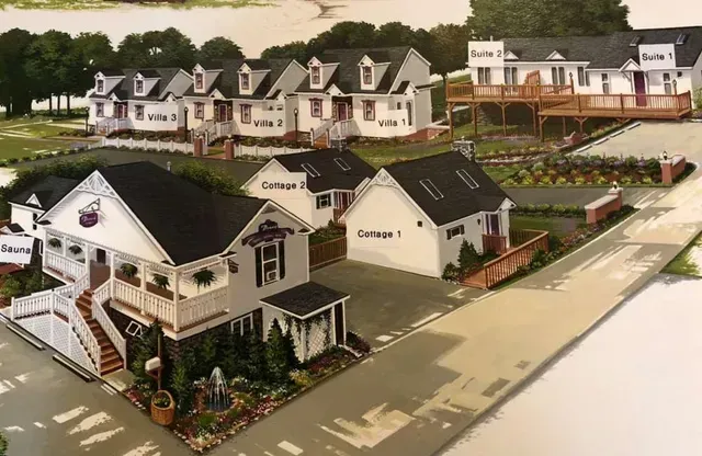 Illustration of a small inn with several white buildings, including cottages and suites, with dark roofs and decks.