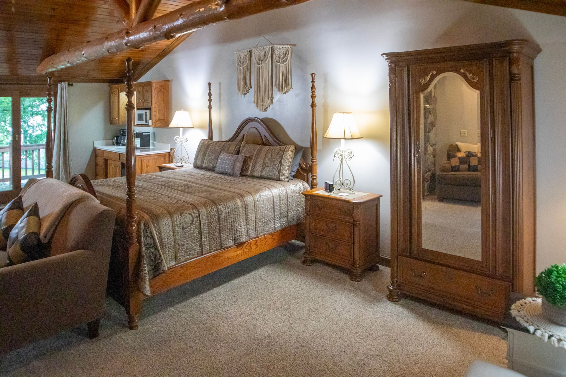Bedroom with canopy bed, sofa, armoire with mirror, and kitchenette.
