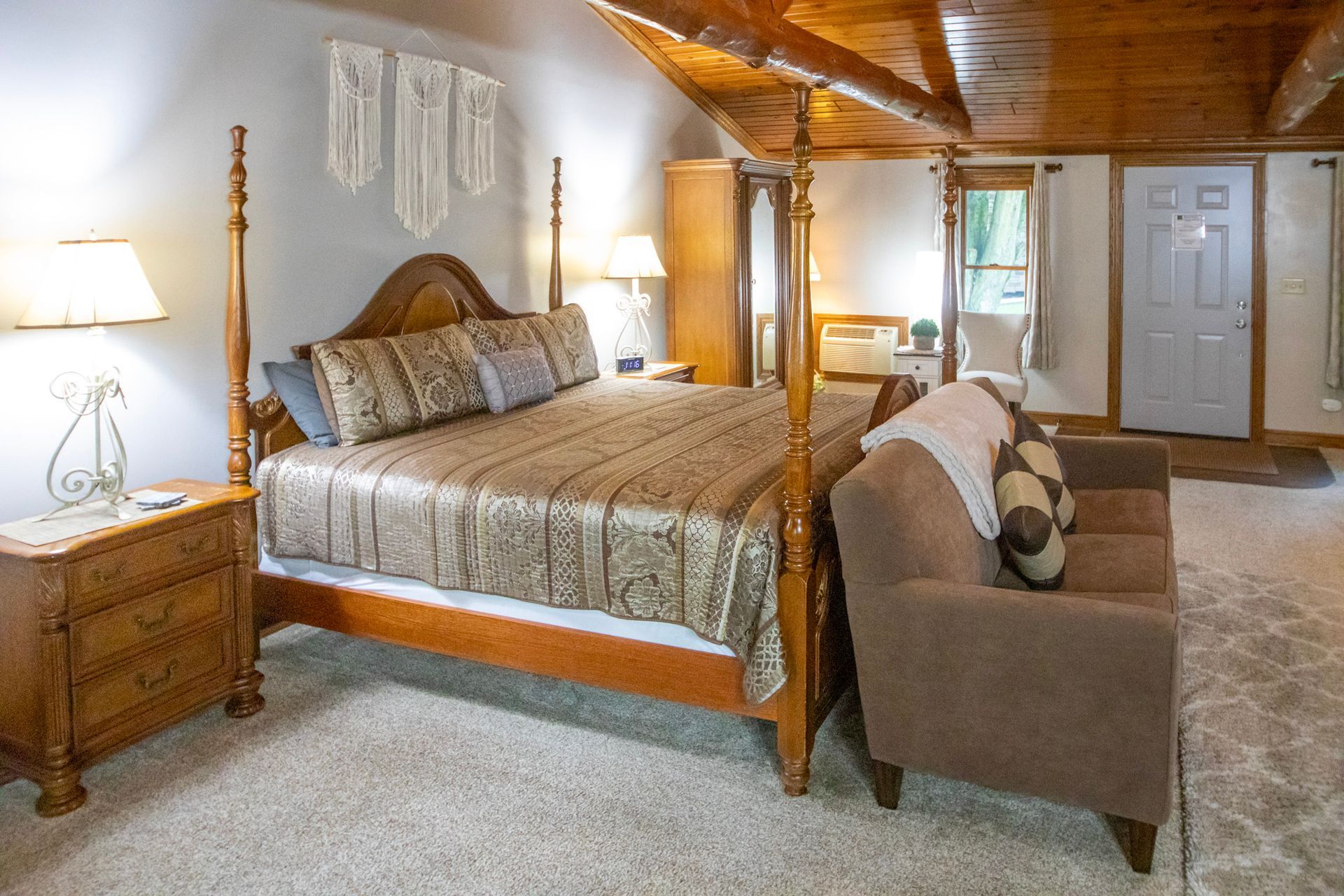 Bedroom with four-poster bed, sofa, wood ceiling, and neutral-toned décor.