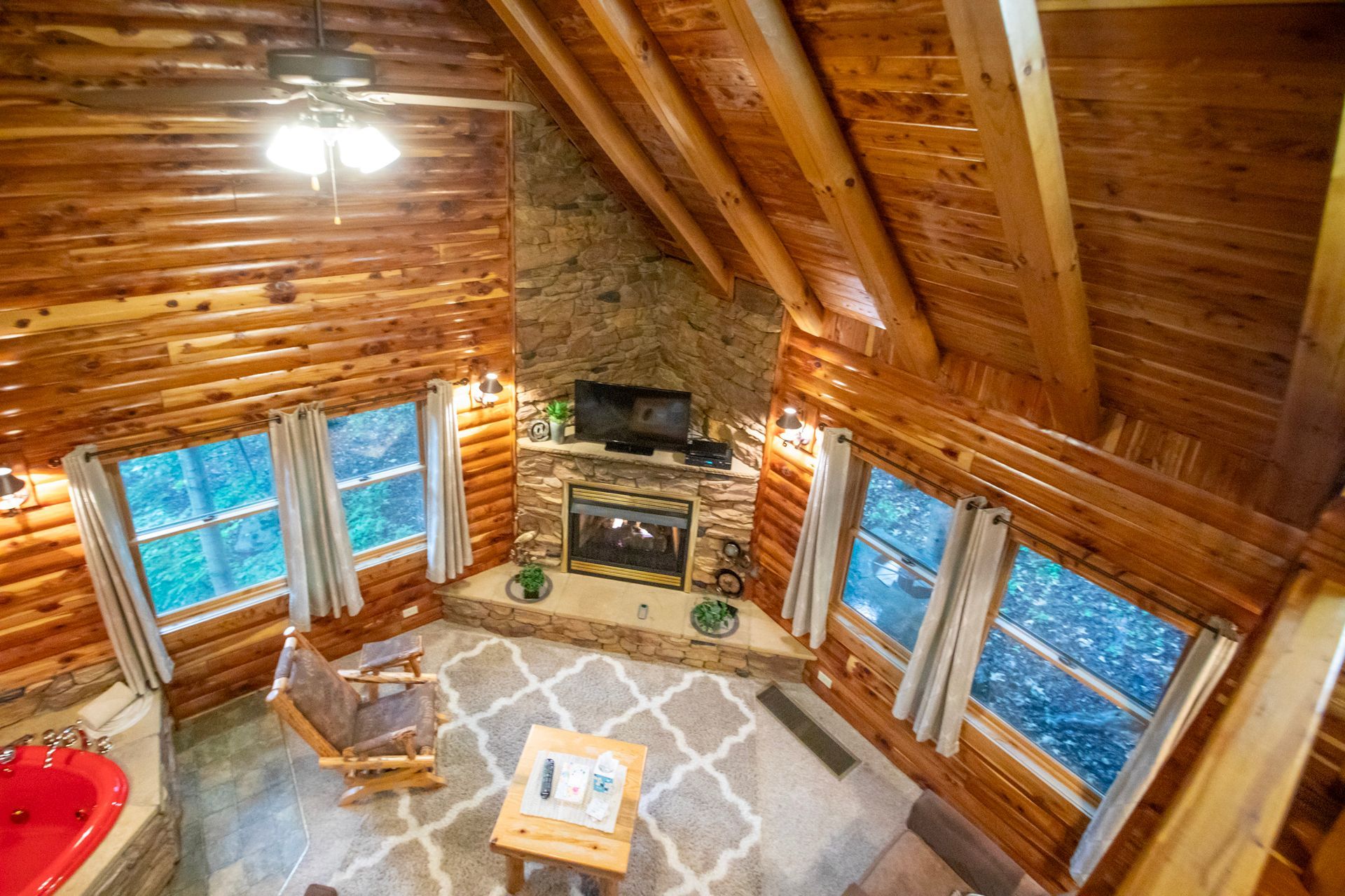 Cozy cabin interior: fireplace, windows, rocking chair, and a spa-like tub.