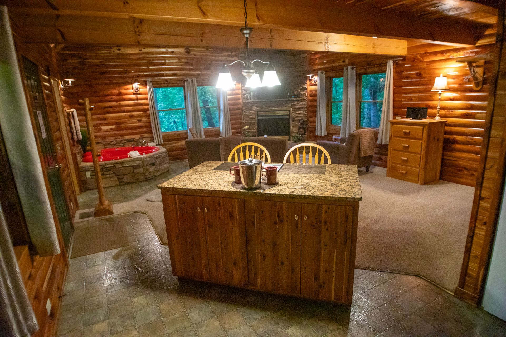 Cozy cabin interior with a kitchen island, fireplace, and log walls.