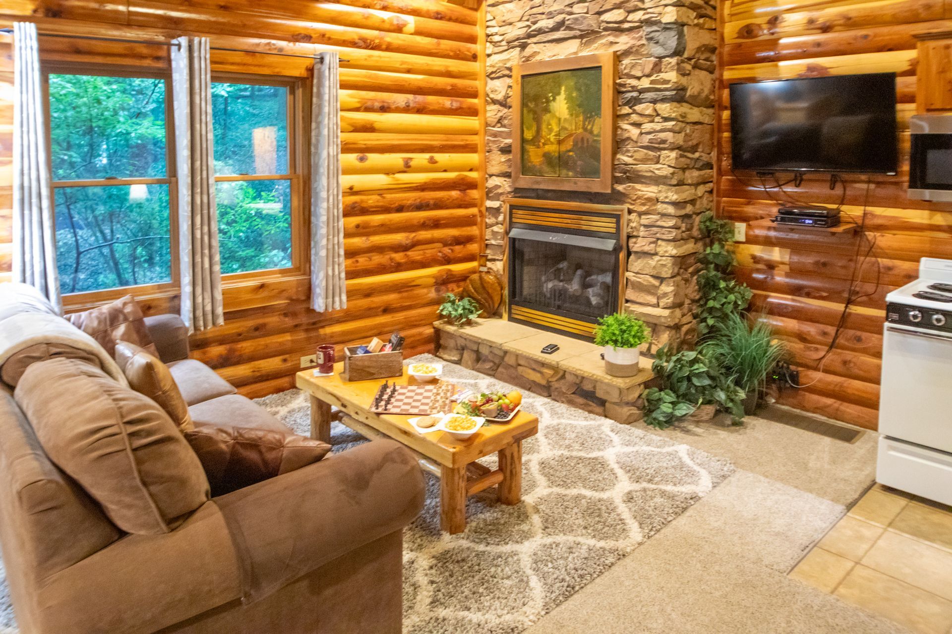 Cozy cabin living room with a stone fireplace, brown sofa, and small wooden table.