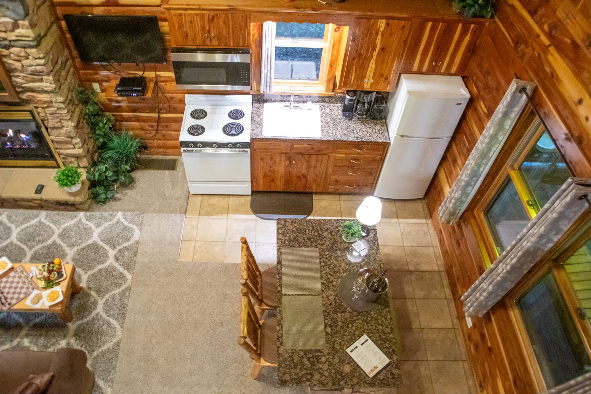 Overhead view of a cabin interior with a kitchen, dining table, and living room with a fireplace.