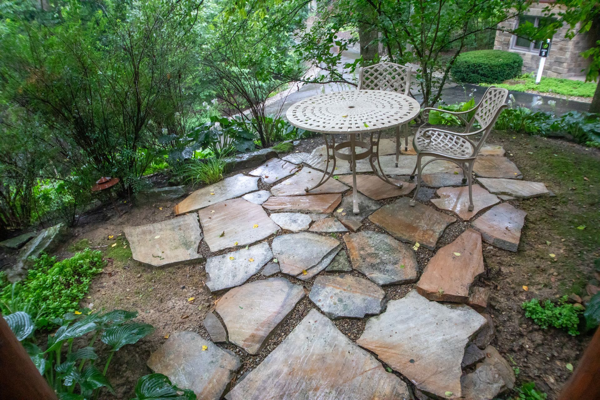 Stone patio with a table and chairs in a garden. Overcast day.