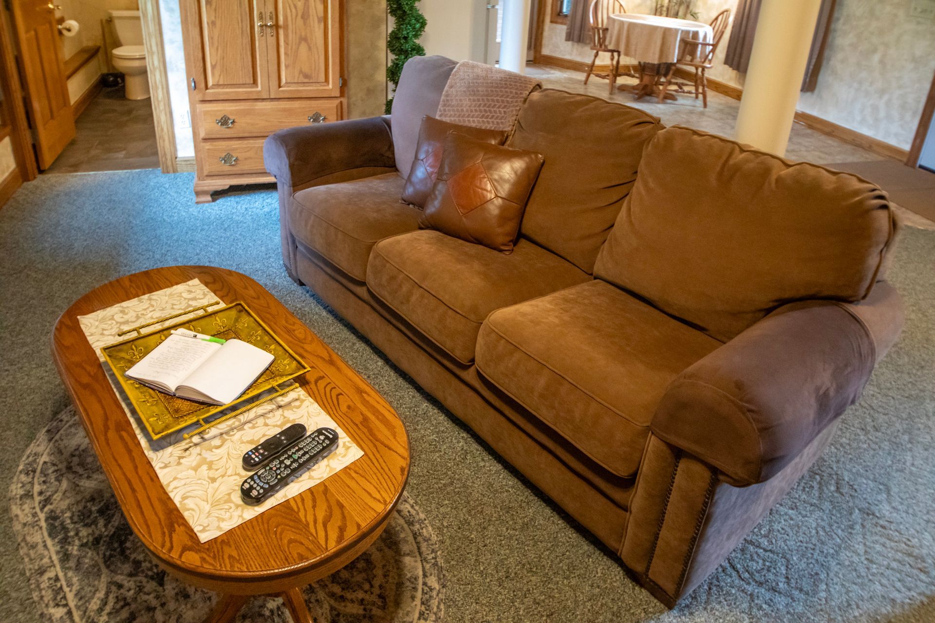 Cozy living room with brown sofa, oval coffee table, and light blue carpet.