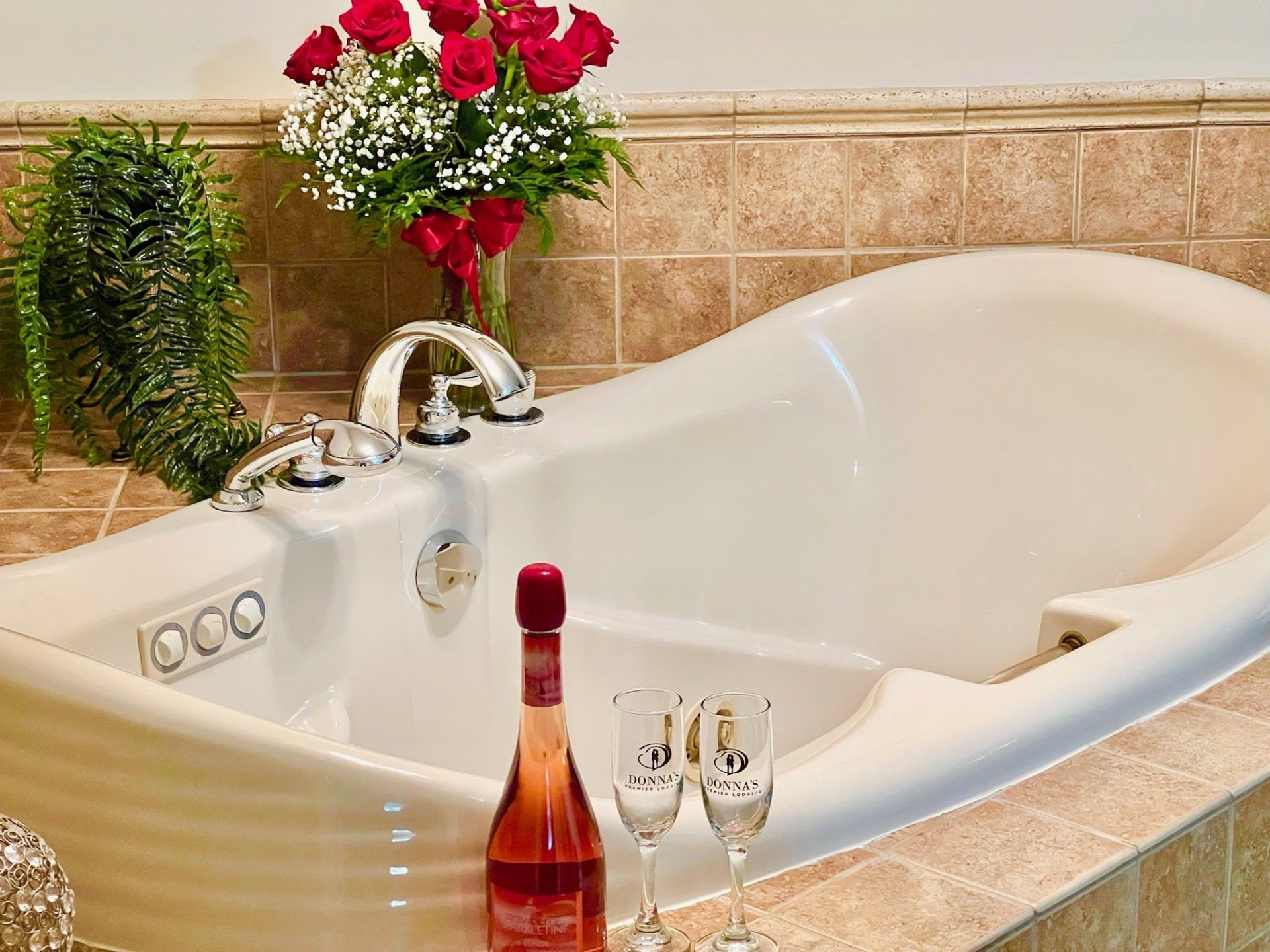 Bathtub with flowers, champagne, and glasses, suggesting a relaxing, romantic setting.