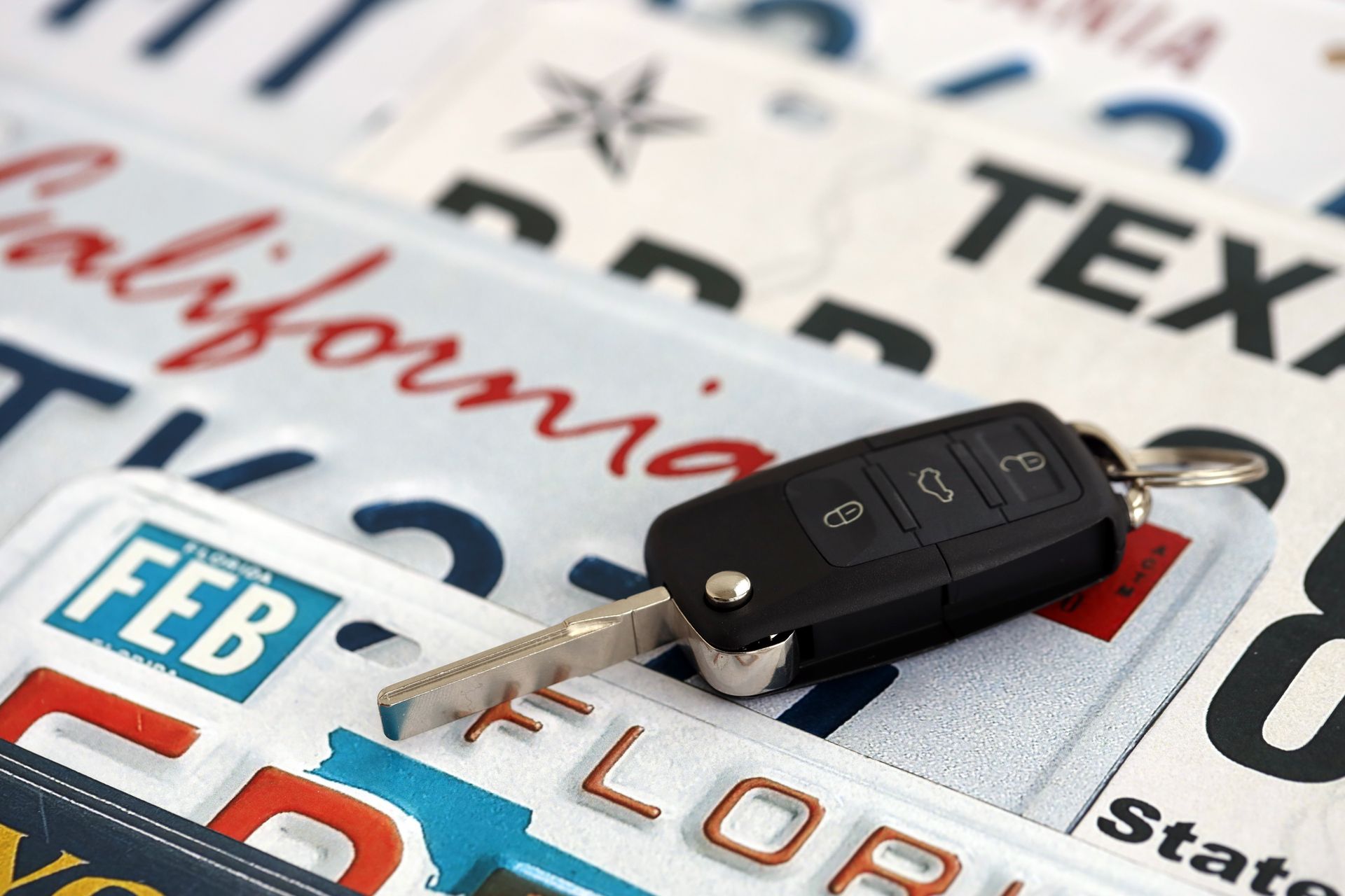 Car keys on a pile of license plates from various US states. Car keys on a pile of license plates from various US states.