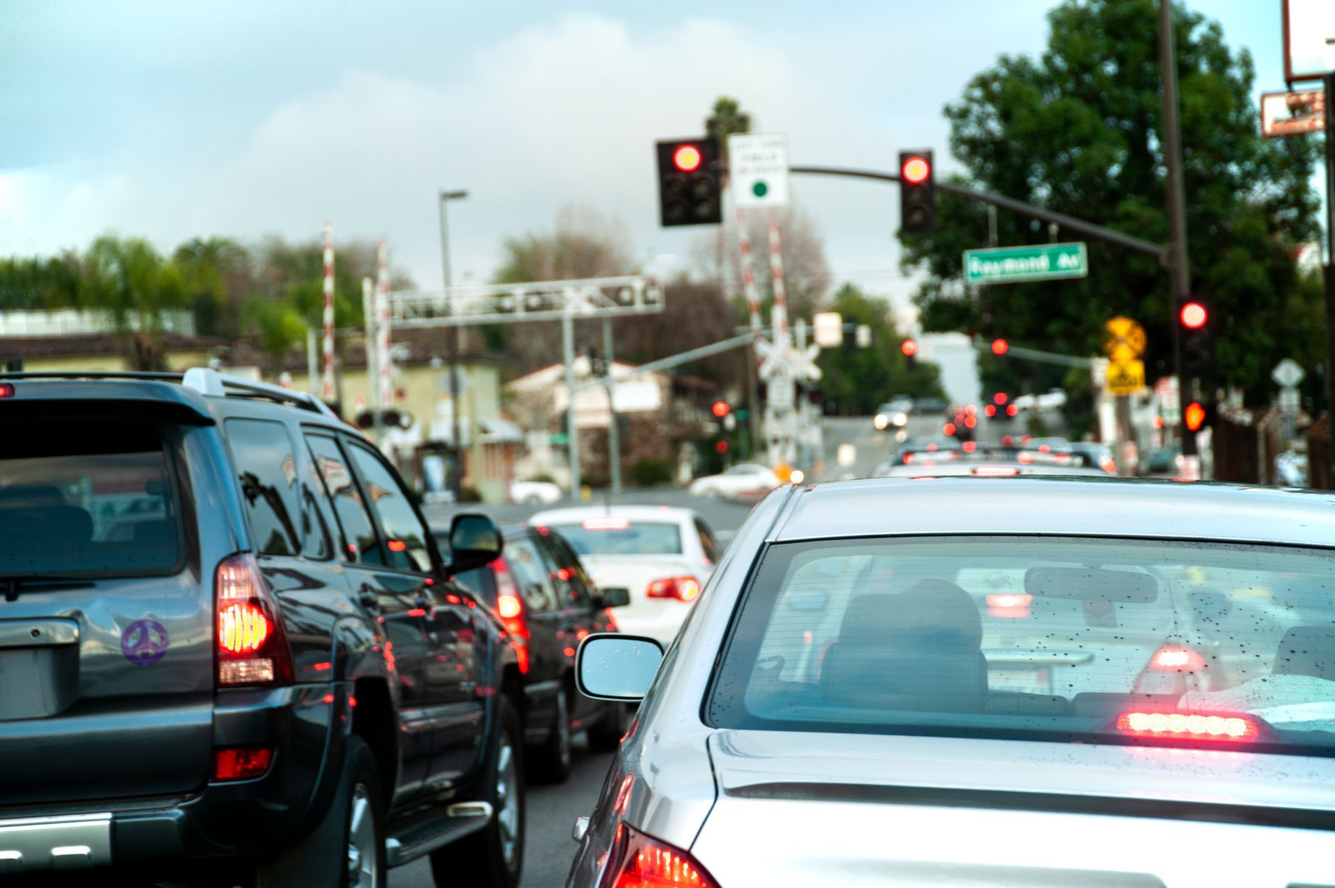 Cars stopped at a red traffic light, waiting in line on a street with a railroad crossing in the background. Cars stopped at a red traffic light, waiting in line on a street with a railroad crossing in the background.