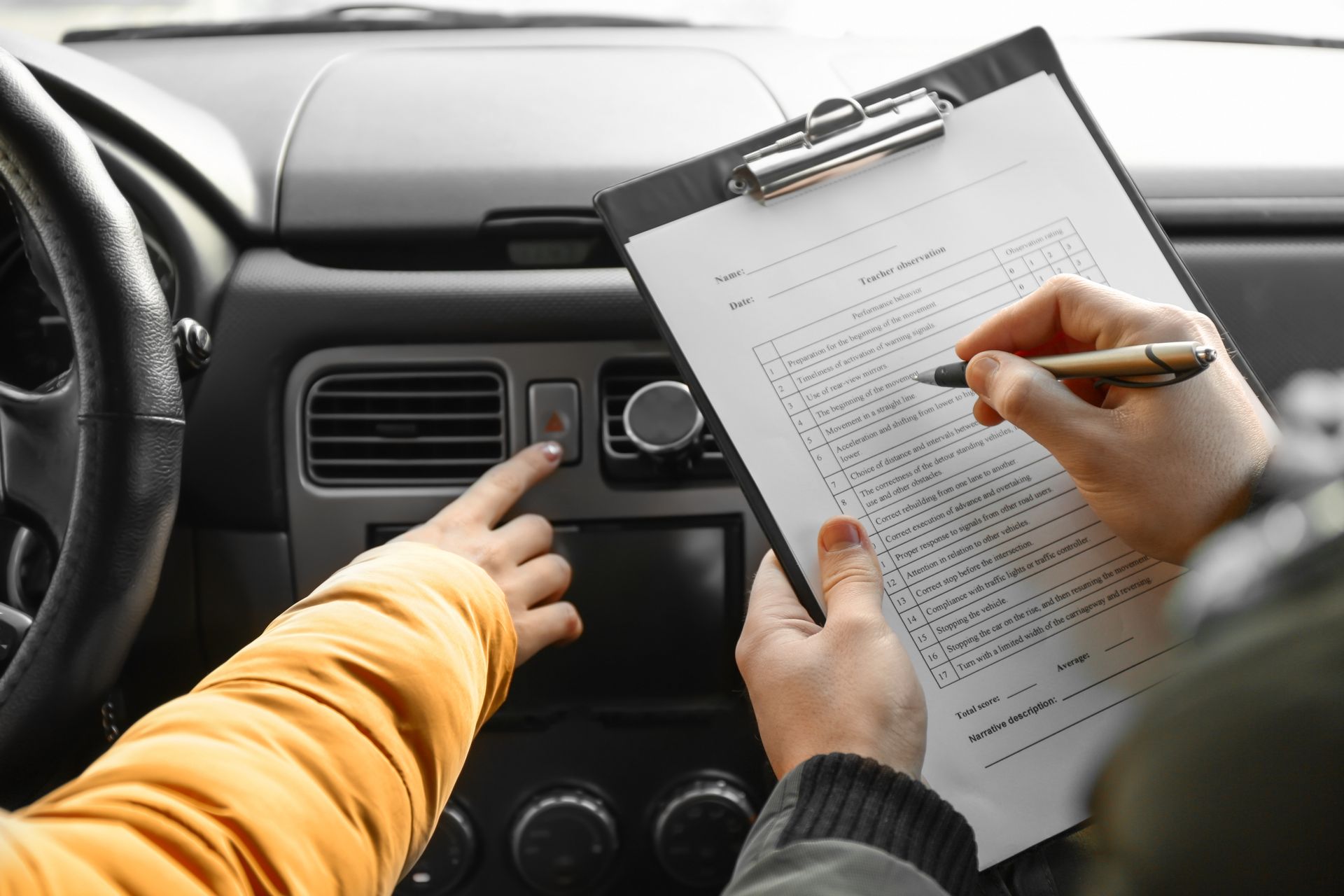 Person in car pointing at a button while another person marks a clipboard. Person in car pointing at a button while another person marks a clipboard.