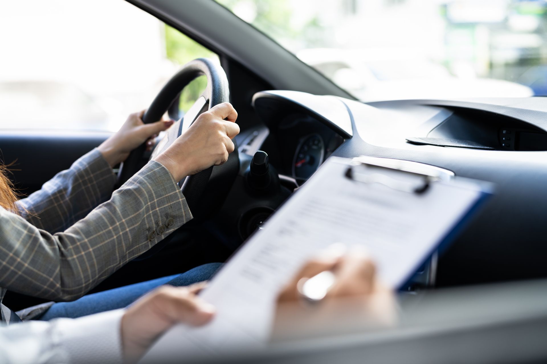 Person driving a car during a driving test, with an examiner holding a clipboard. Person driving a car during a driving test, with an examiner holding a clipboard.