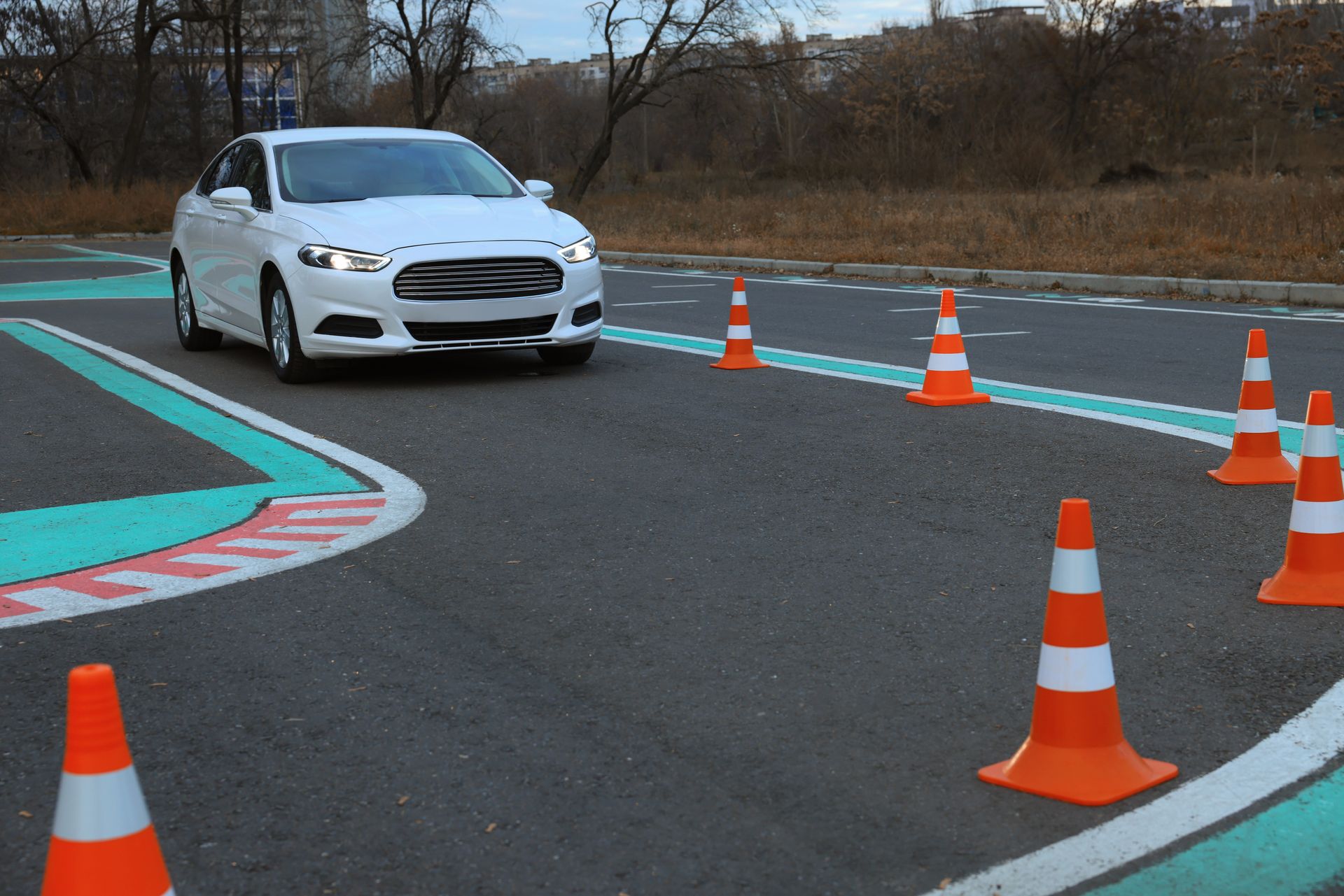 White car driving through driving test course with orange cones. White car driving through driving test course with orange cones.