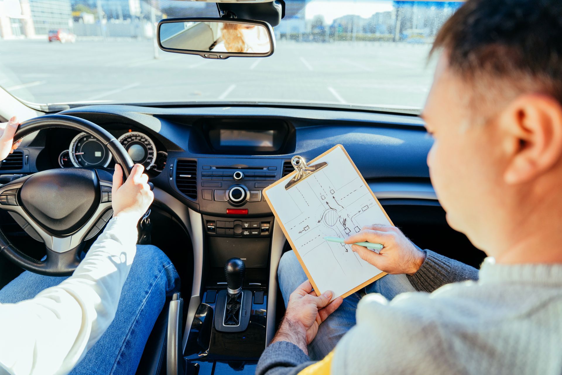 Driver in car with instructor, studying driving instructions on a clipboard. Driver in car with instructor, studying driving instructions on a clipboard.