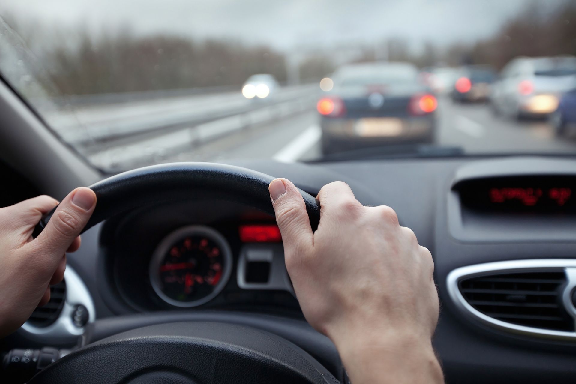 Hands gripping a car steering wheel; driving on a highway with other vehicles. Hands gripping a car steering wheel; driving on a highway with other vehicles.