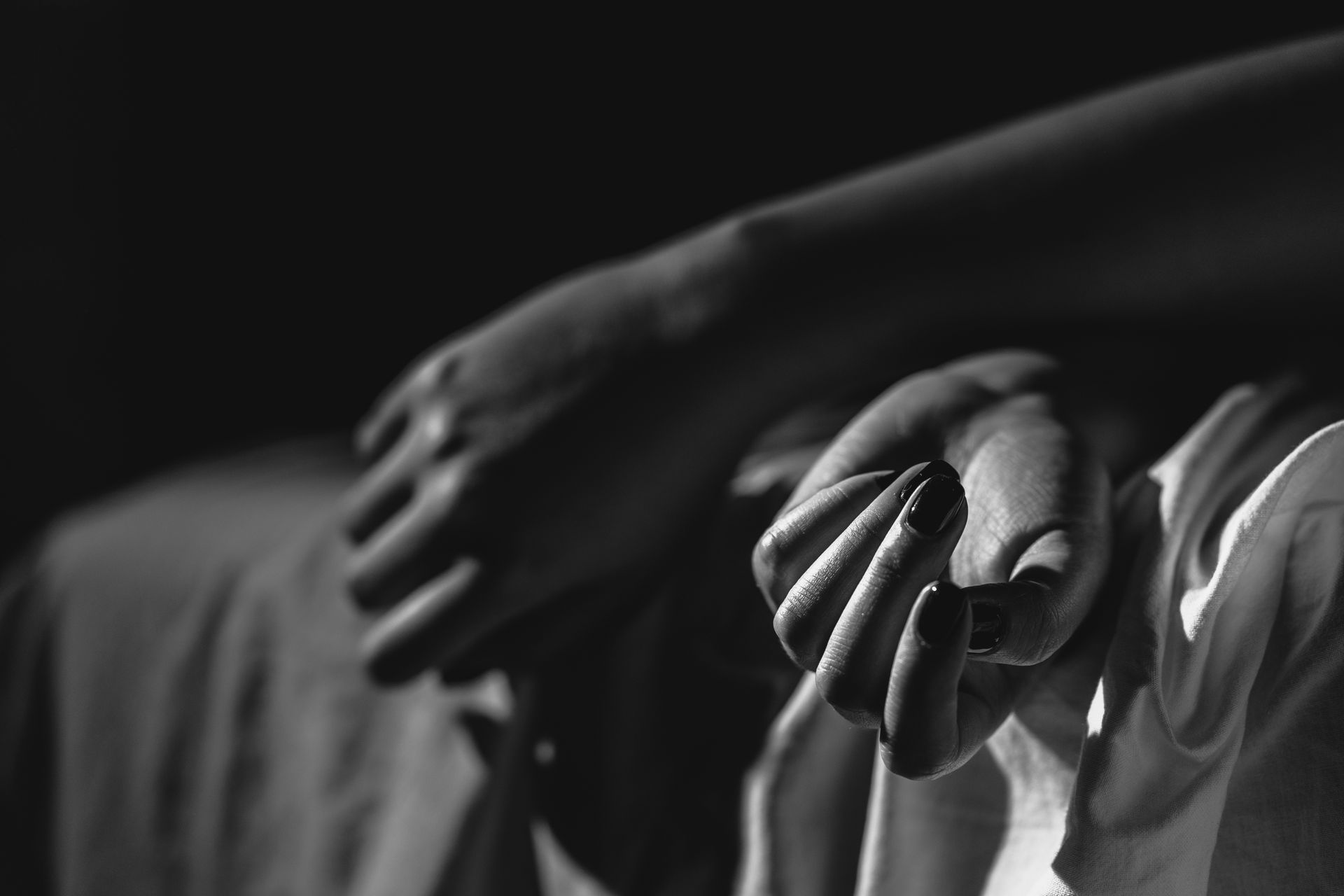 A black and white photo of a person holding another person 's hand.