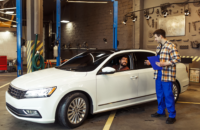 Mechanic talking to a customer in a white car | GenAuto