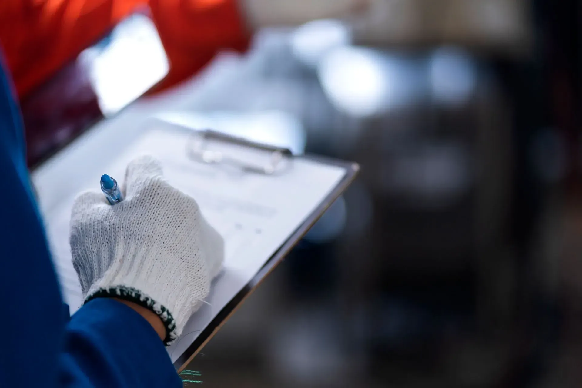A person wearing gloves is writing on a clipboard on a roof in bakersfield