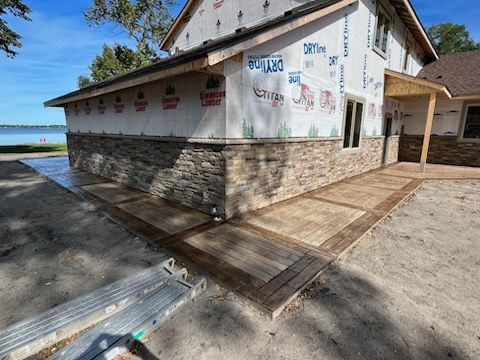 New building exterior with stone base, white walls, and a ramp walkway by the water
