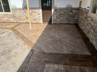 Stone and wood patio leading to a front door, with a brick exterior wall and porch posts