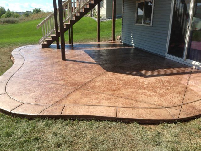 Stamped concrete patio beside a house with stairs and a wet surface after rain.
