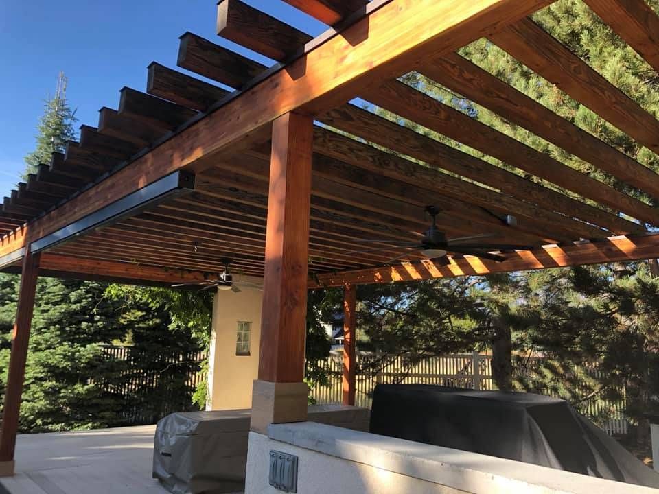 a wooden pergola with a grill underneath it