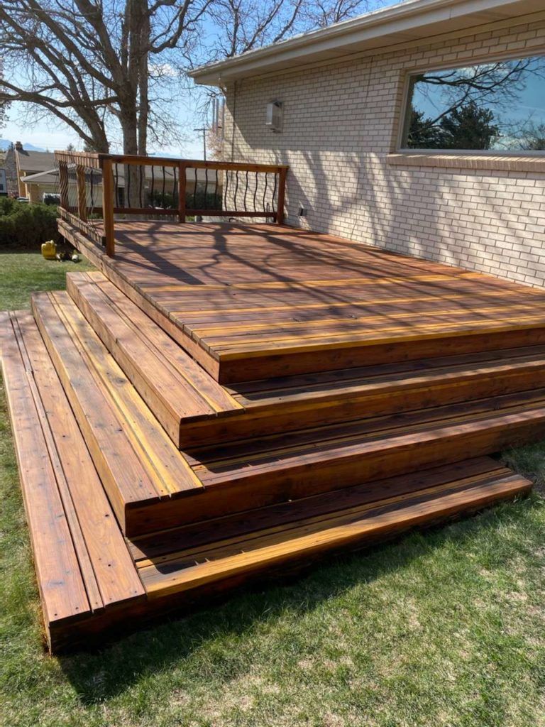 a wooden deck with stairs leading up to it is in front of a house .
