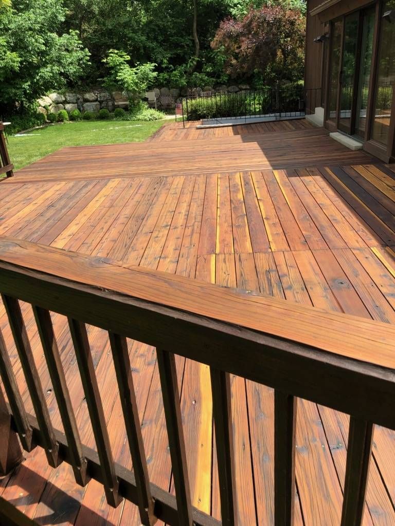 a wooden deck with a railing in the backyard of a house .