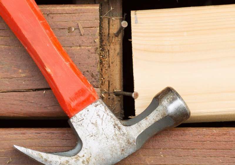 a hammer is being used to hammer a nail into a piece of wood .