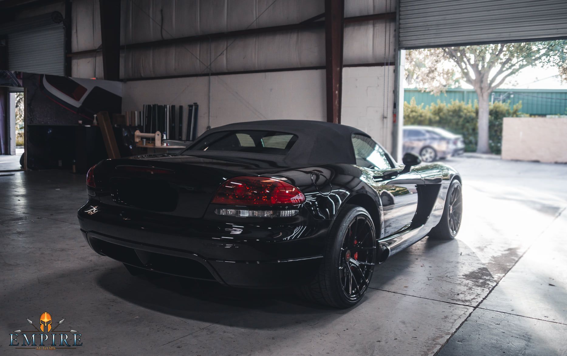 A black dodge viper convertible is parked in a garage.