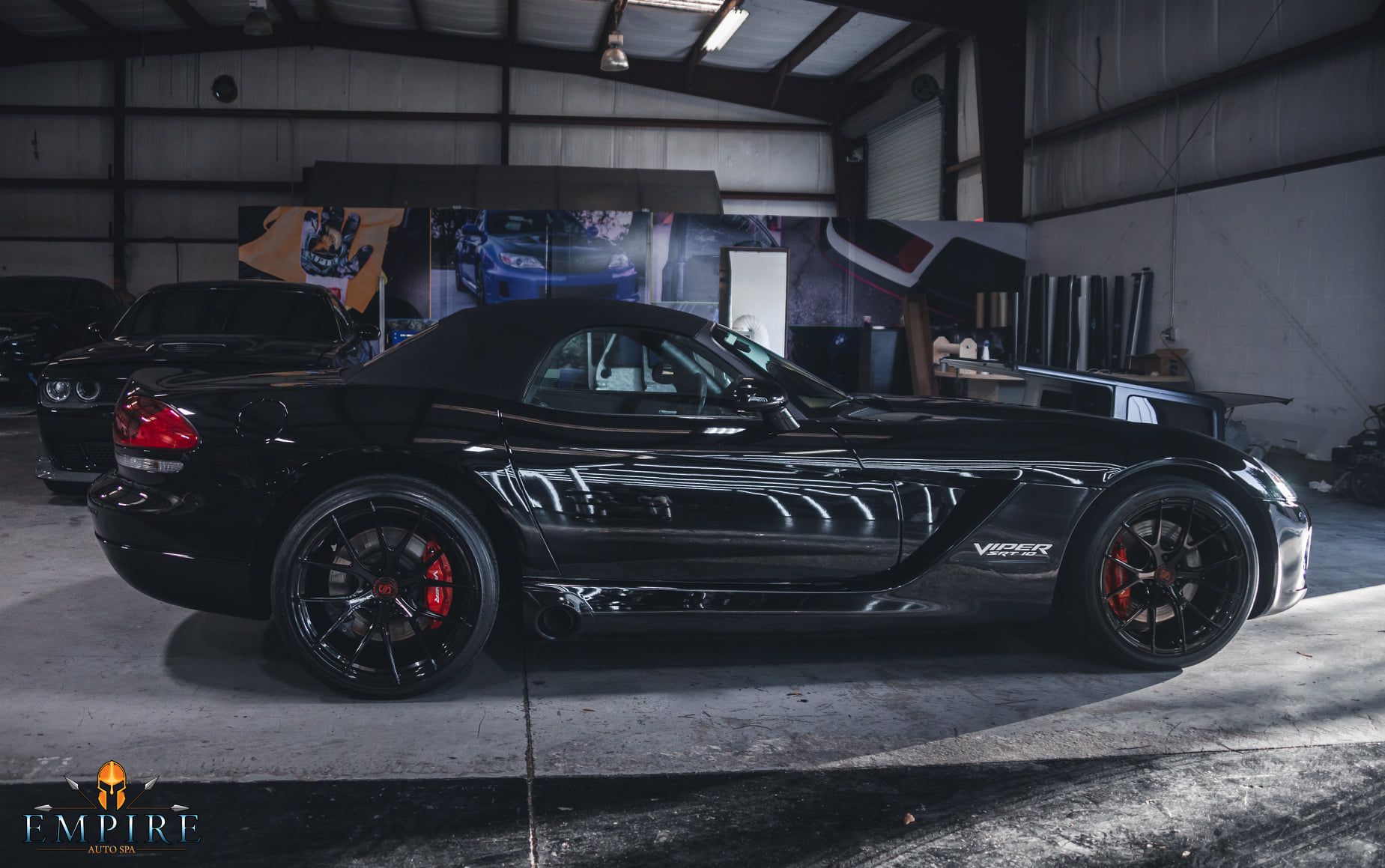 A black dodge viper convertible is parked in a garage.