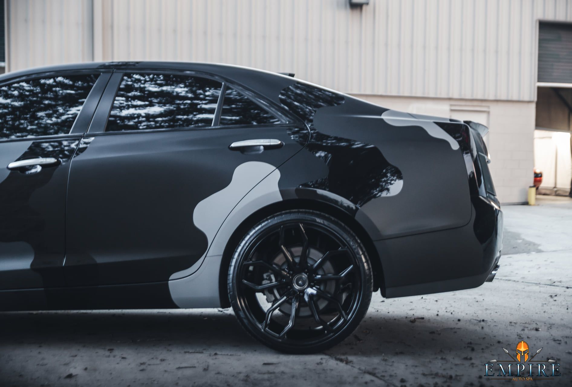 A black car is parked in front of a building.