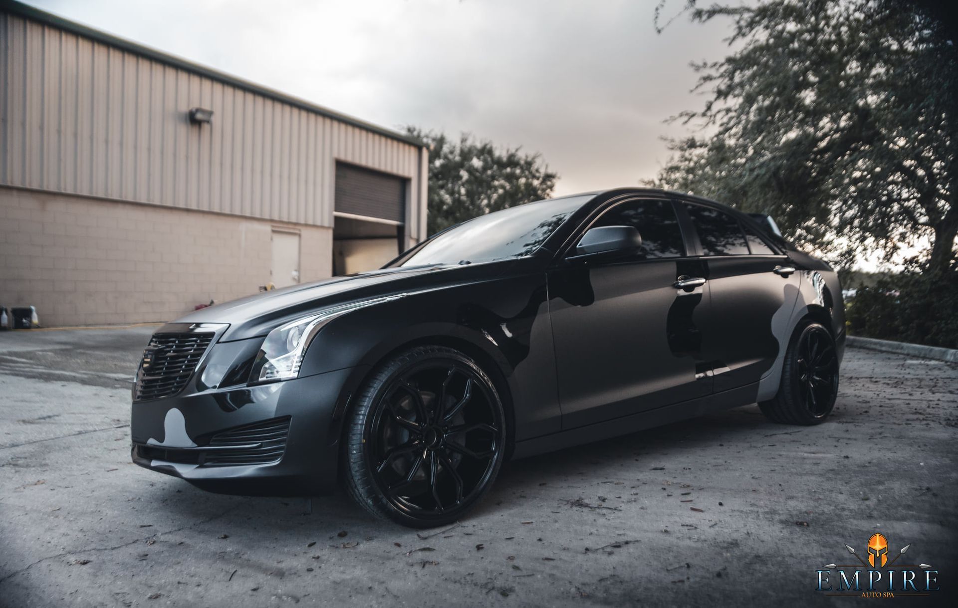 A black car is parked in front of a building.