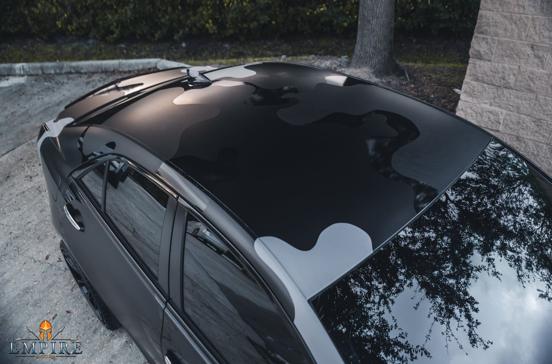 A black car with a black roof is parked in a parking lot