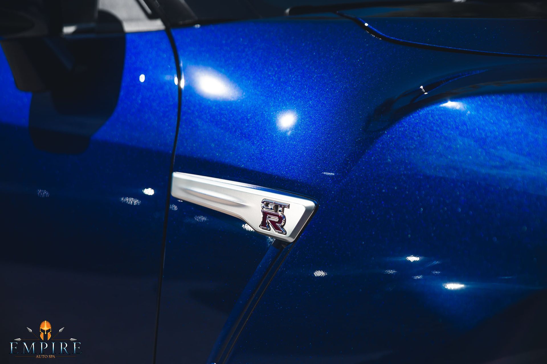 A close up of a blue car with a nissan logo on the side