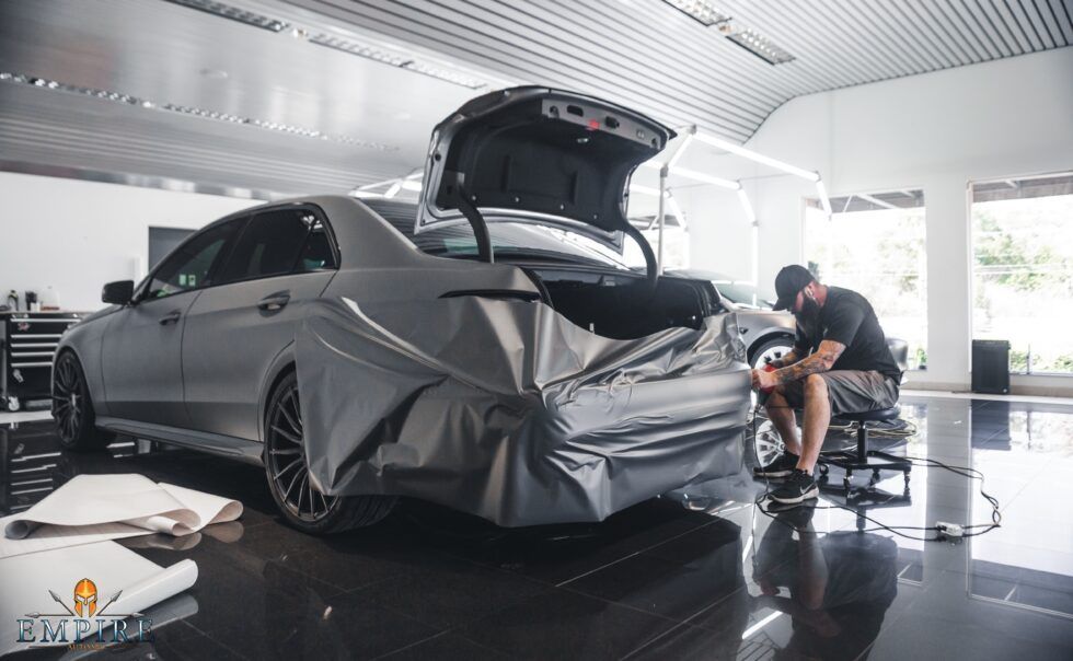 A man is wrapping a car in a garage.