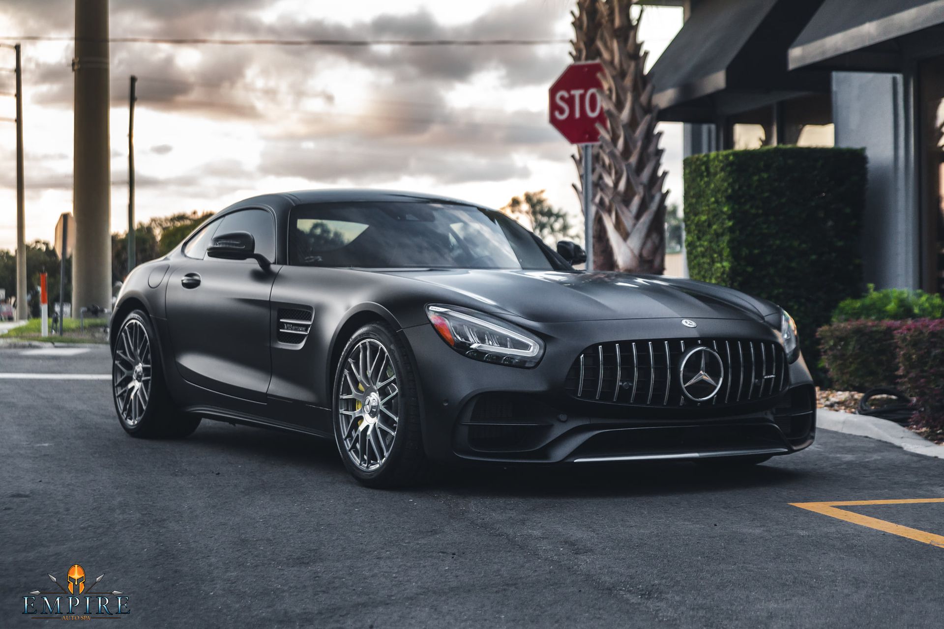A black mercedes amg gt is parked in front of a stop sign.