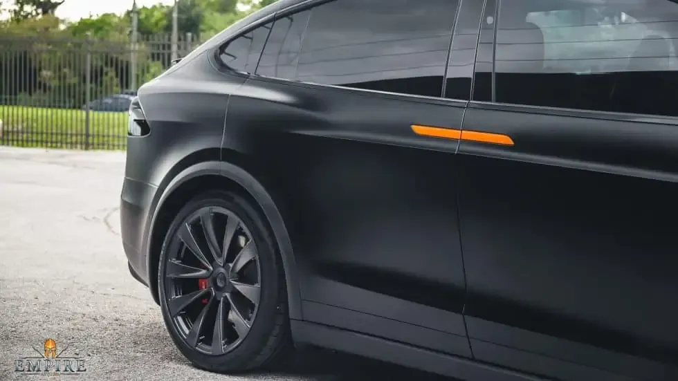 A black tesla model x is parked in a parking lot.