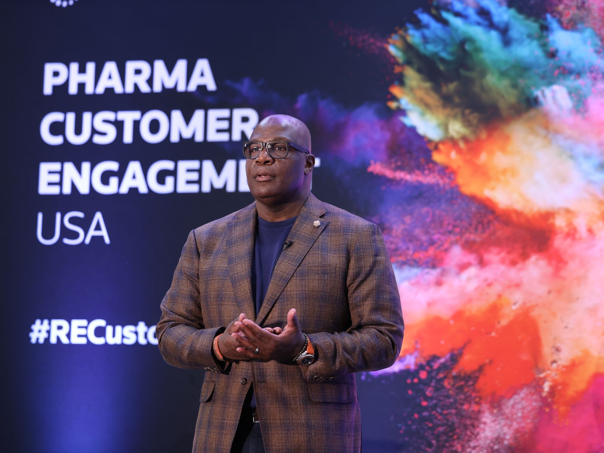 Man speaking at a conference. Text: Pharma Customer Engagement USA. Colorful background.