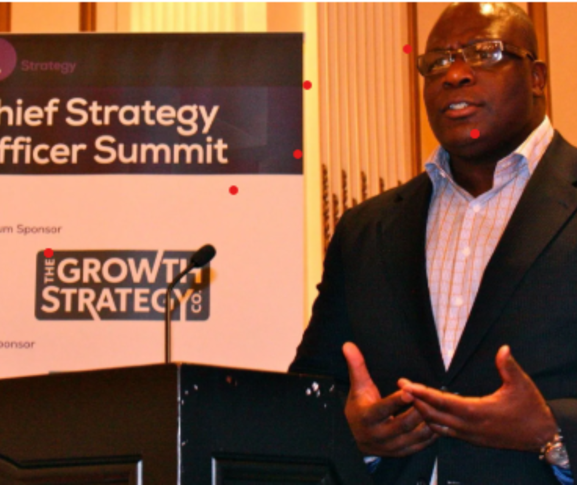 Speaker at podium during Chief Strategy Officer Summit, with orange-lit conference backdrop and GROWTH Strategy logo
