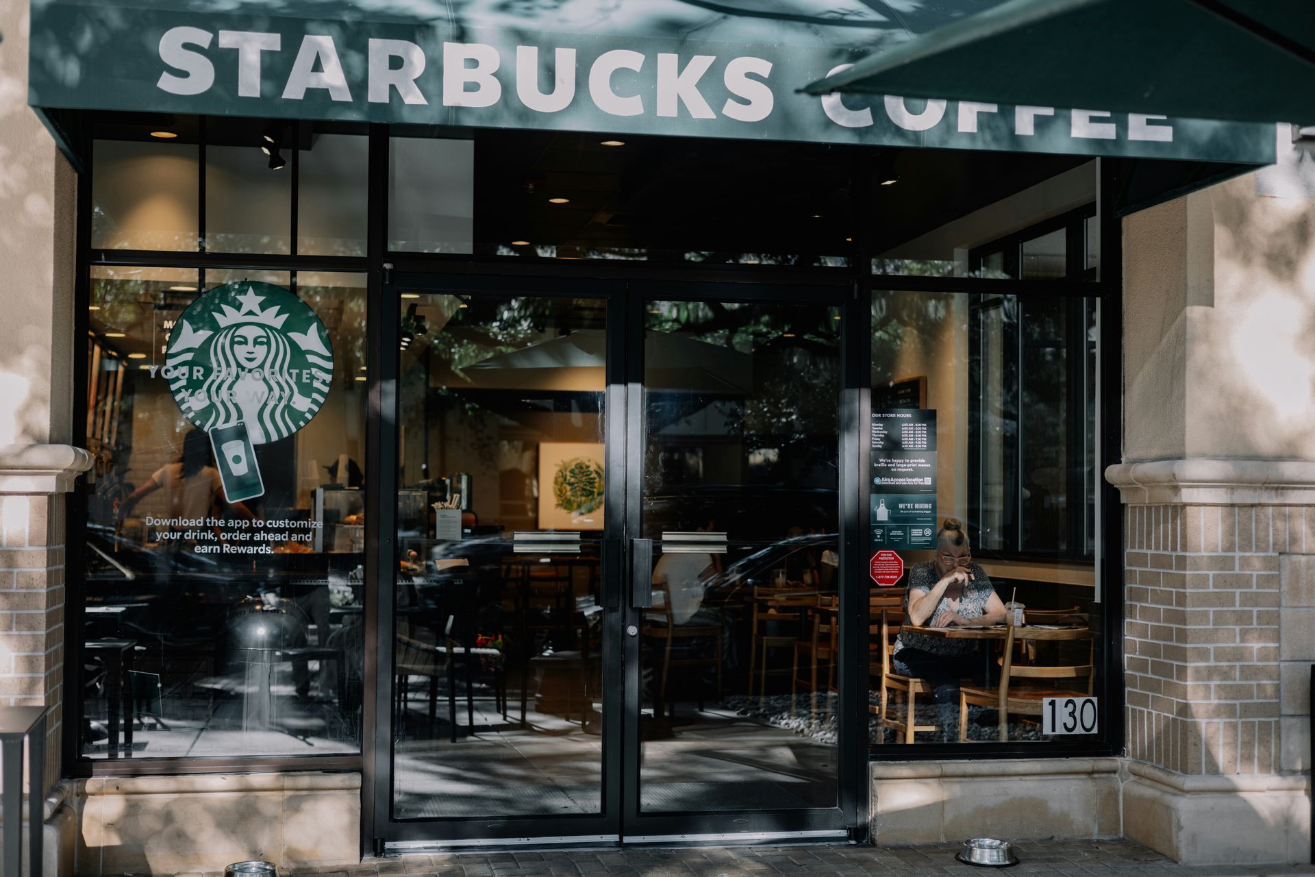 Starbucks coffee shop storefront with glass doors and logo sign above entrance