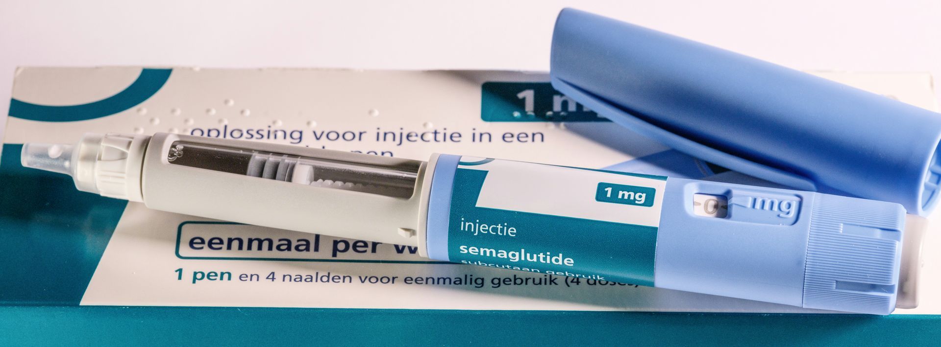 A blue and white tube of cream and a tube cap on a white surface.