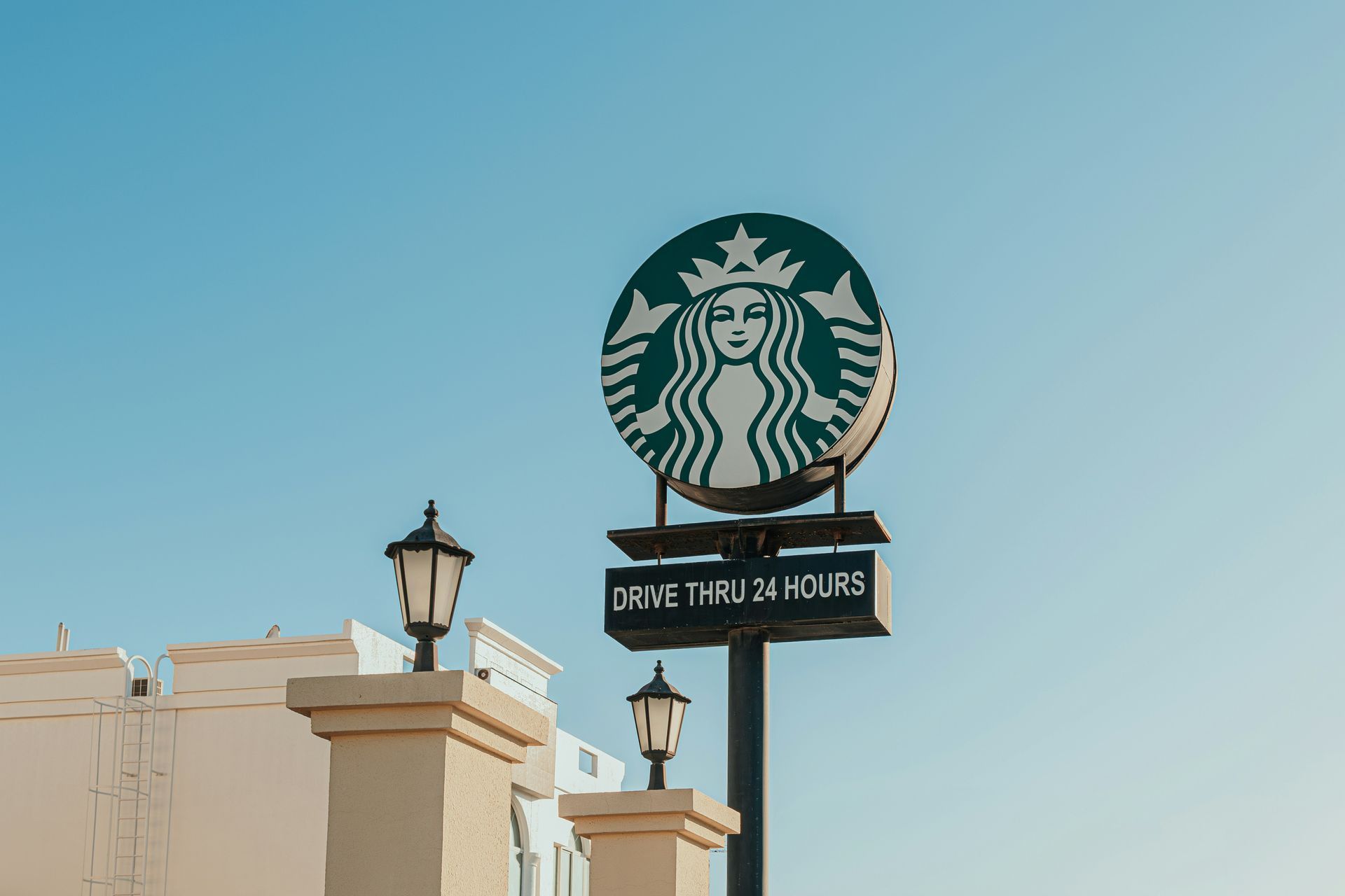 Starbucks sign on a beige building against a clear blue sky