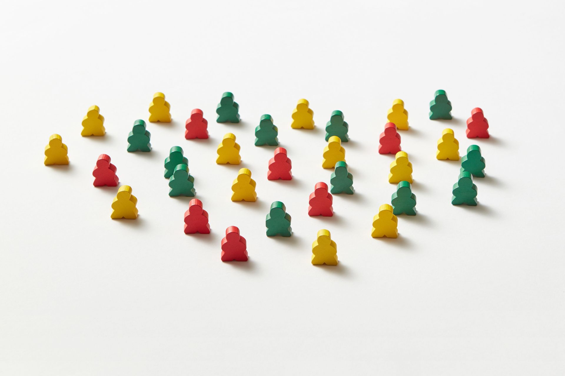 Small red, yellow, and green figurines arranged in rows on a white surface.