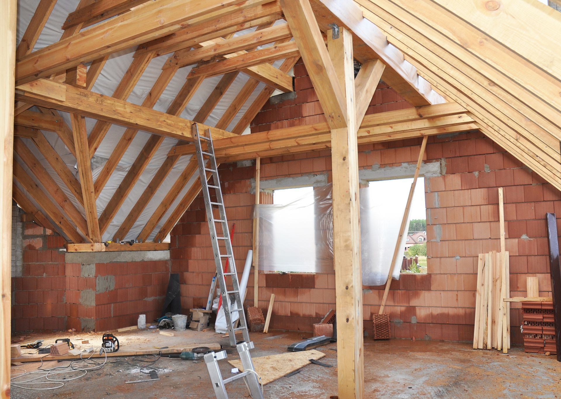 An attic under construction with a wooden roof and a ladder.