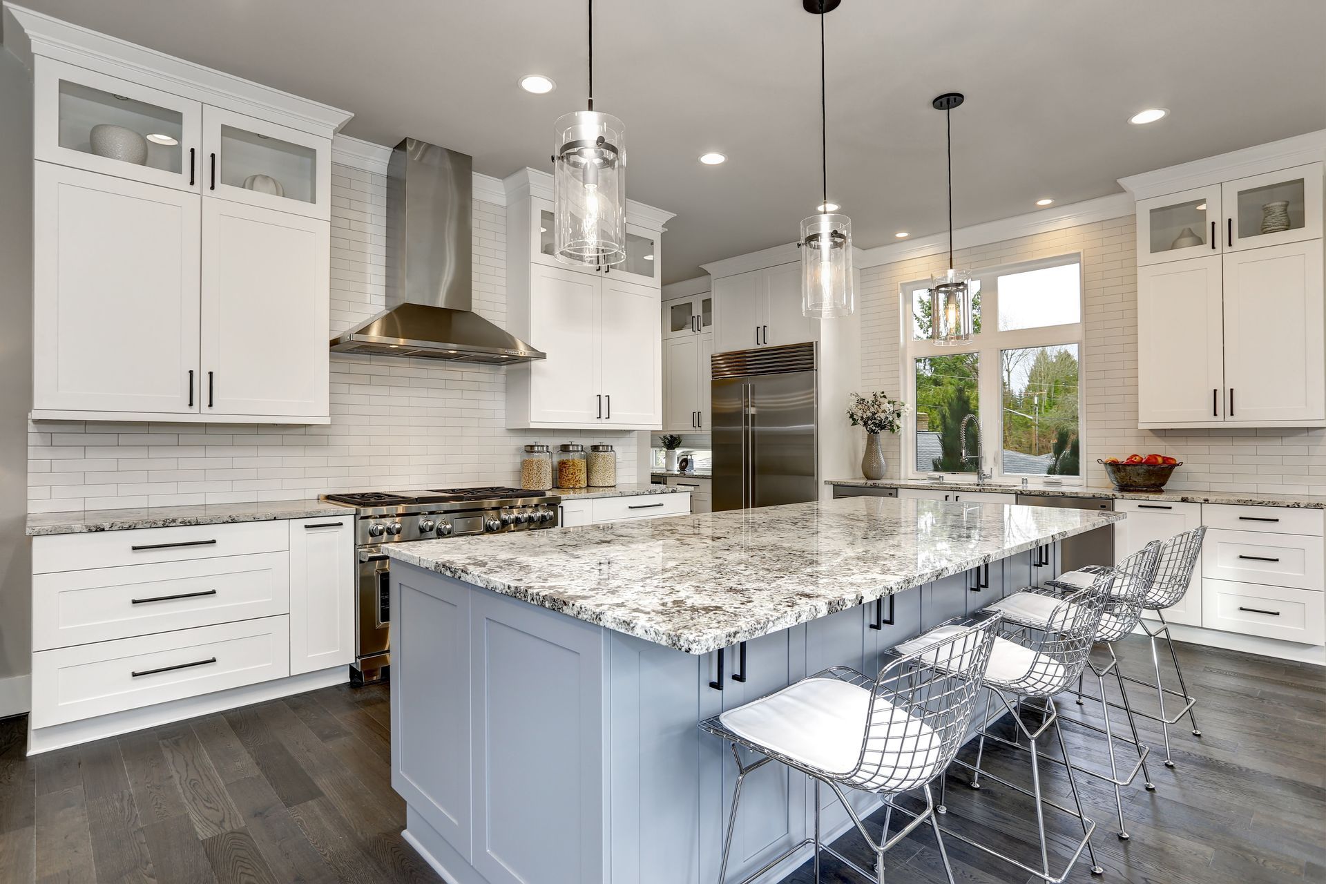 A kitchen with white cabinets , granite counter tops , stainless steel appliances and a large island.