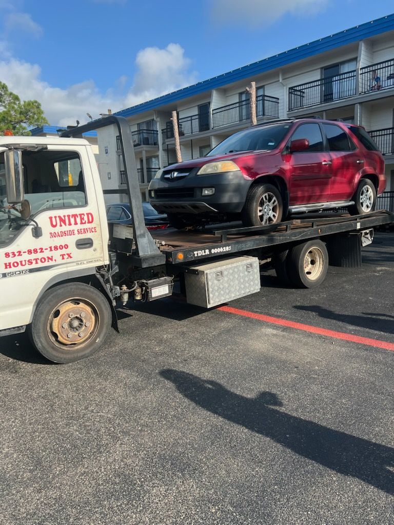 Tow truck loading a red SUV in a parking lot outside a building.