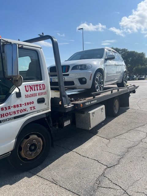 Tow truck lifting a damaged gray car on a city street